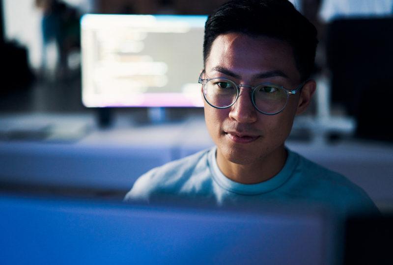 man wearing glasses working at a desktop computer