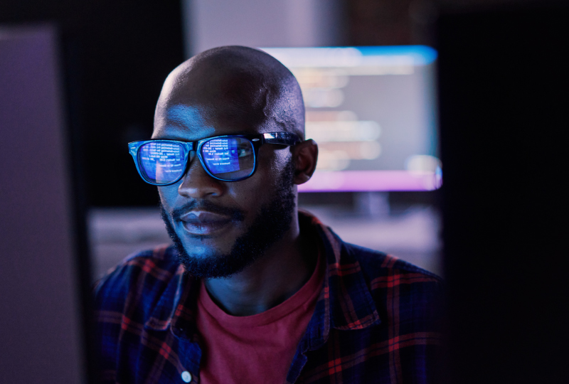 man sitting in a dark office looking at a monitor