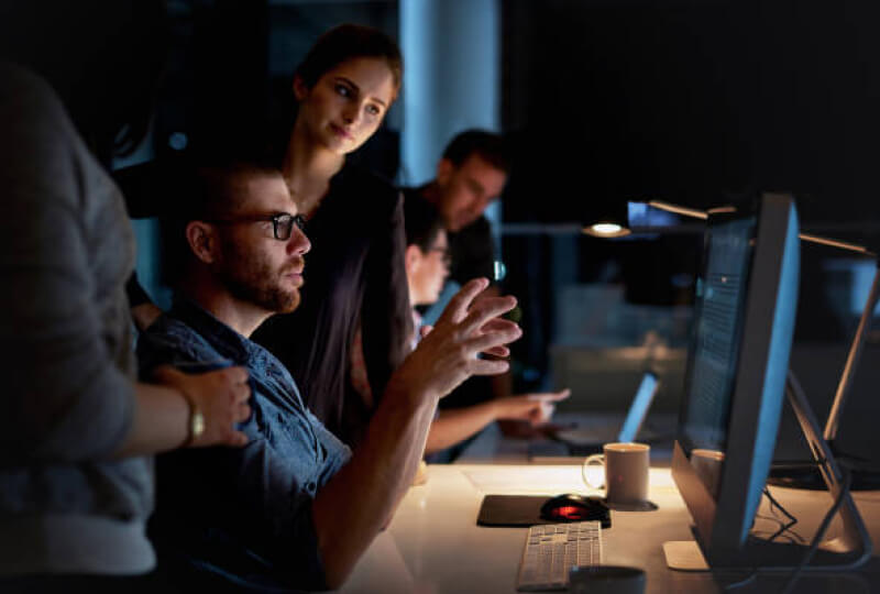 co-workers discussing data one a monitor