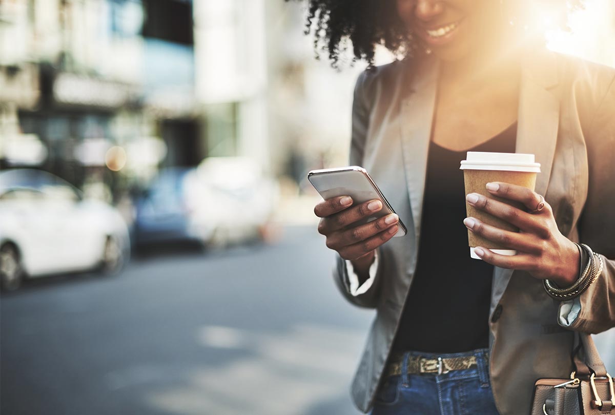 woman holding coffee and a cell phone
