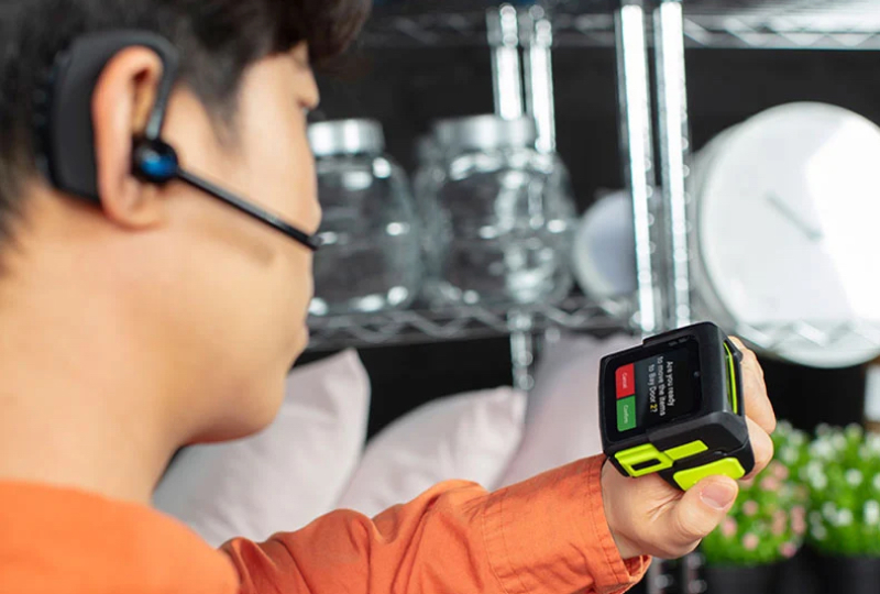 Behind-the-head shot of a worker analyzing the screen of a mobile scanning device held in their left hand.