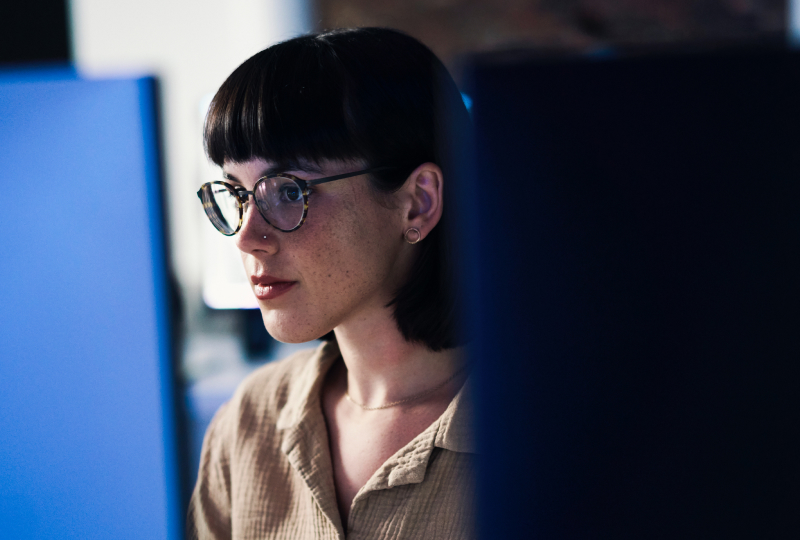 Woman wearing glasses looking intently at a computer display.