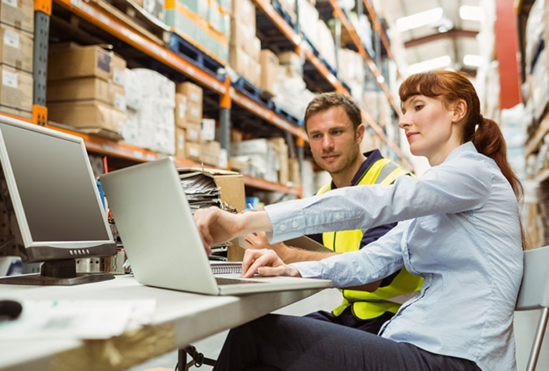 man and woman looking at a laptop in a warehouse